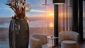 A modern room with a large window, two chairs, a small table, and a vase with flowers. - 2 Modern Haven, Steps from City Center, Shops | Scenic Nature Trails Nearby (Amsterdam)