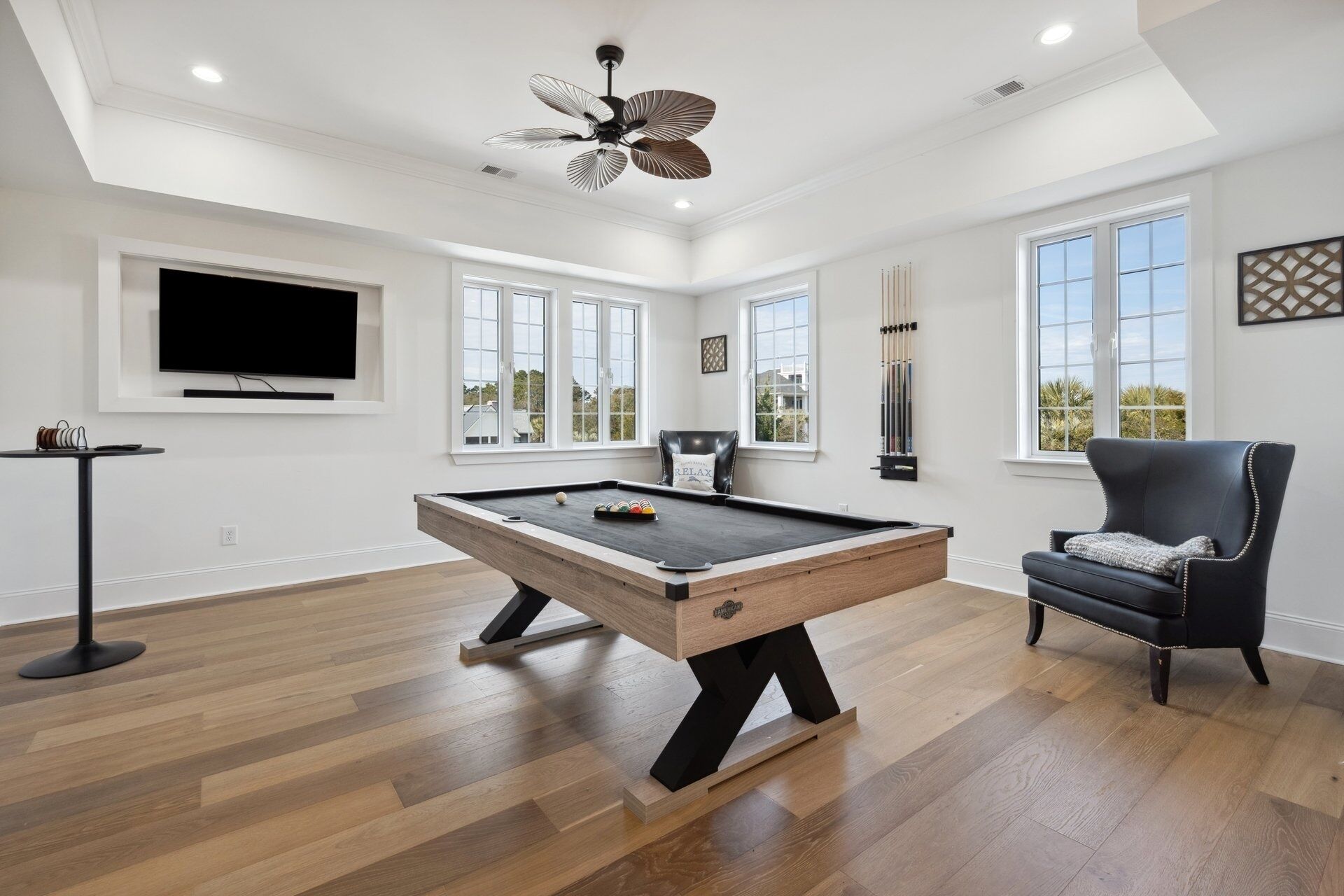A spacious room with a pool table, a comfortable armchair, and a television mounted on the wall.
