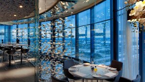 En moderne restaurant med panoramaudsigt over byen, med en unik glasvæg og hængende sfæriske dekorationer.