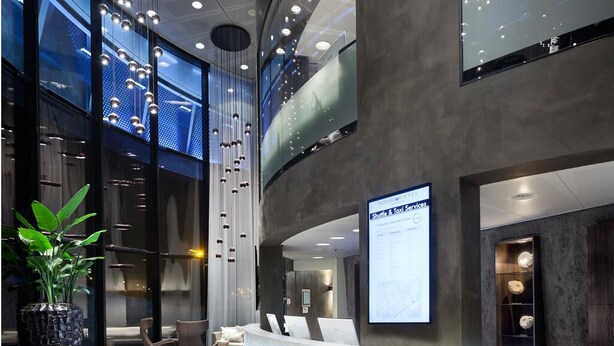 En moderne hotellobby med reception, siddeområde og store vinduer.