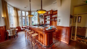 A bar area with wooden bar stools, a bar counter, and hanging pendant lights. - Stay in Style with On-Site Bar, Breakfast Service, Near Speelgoedmuseum (Deventer)