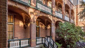 A courtyard with a brick building featuring arched windows and balconies, outdoor seating, and a staircase leading to an upper level. - Stay in Style with On-Site Bar, Breakfast Service, Near Speelgoedmuseum (Deventer)