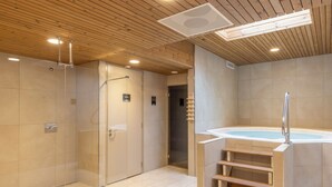 Une salle de bain moderne dotée d’une douche à parois de verre, d’une baignoire à porte et d’un escalier en bois menant à un bain à remous.