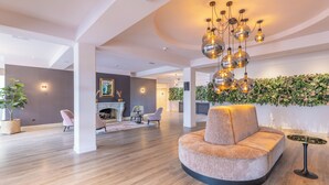 Un vaste espace de vie agrémenté d’un canapé moderne, d’une cheminée et d’un mur décoratif orné de plantes.