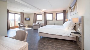 Een hotelkamer met een groot bed, een bureau, een stoel en een televisie.