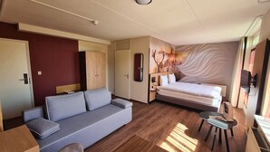 A modern hotel room with a sofa, a bed, a small table, and a mirror. - Nature lover's getaway | Dining spots | Burgh-Haamstede, Strand bij Ouddorp (Burgh-Haamstede)