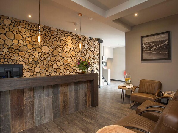 A reception area with a wooden log wall, a reception desk, leather chairs, and a framed picture on the wall.