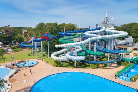 A water park with multiple water slides, a swimming pool, and a sandy area with lounge chairs.