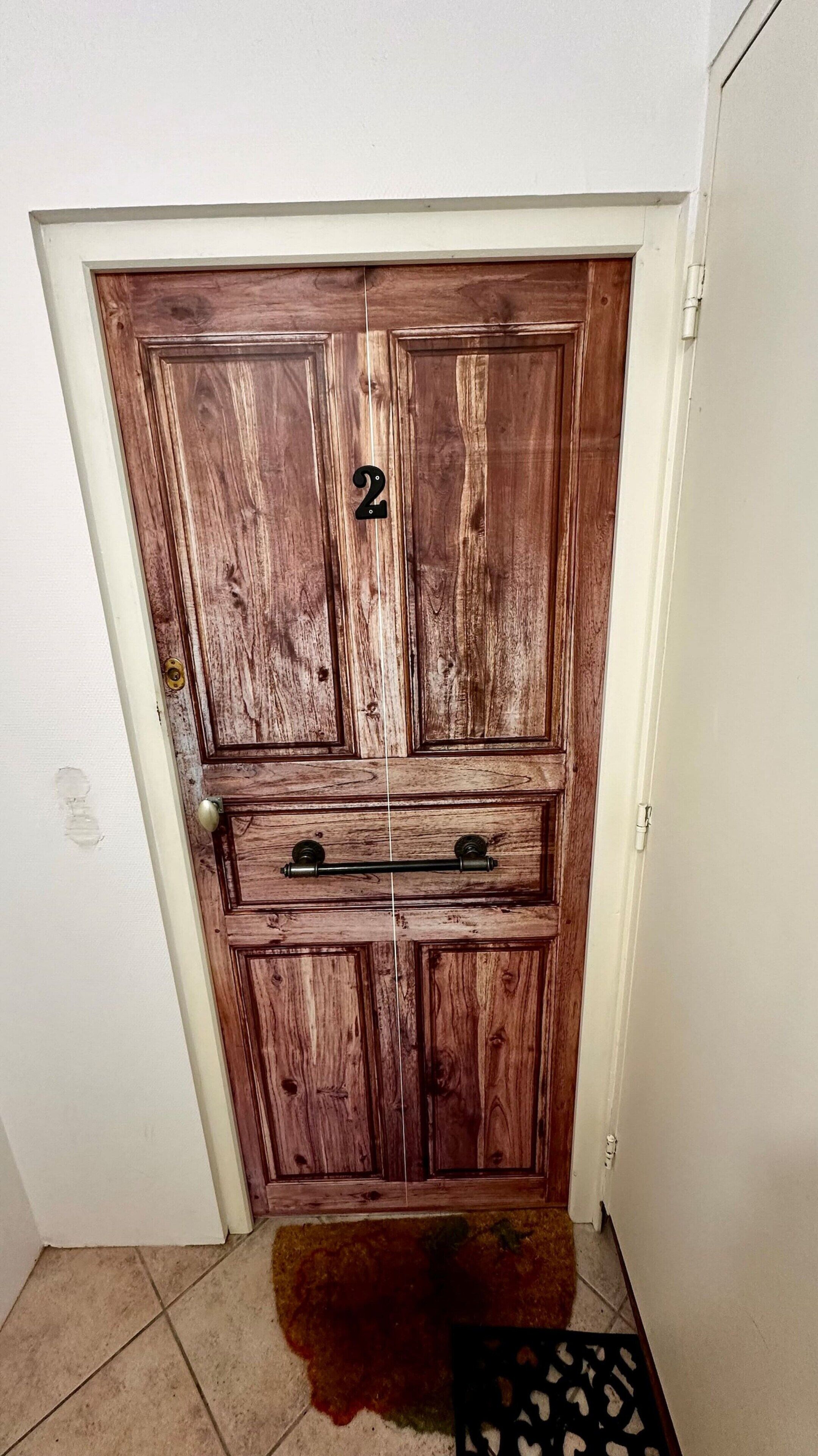 Una porta de fusta amb el número 2 i un estri de benvinguda a l'entrada.