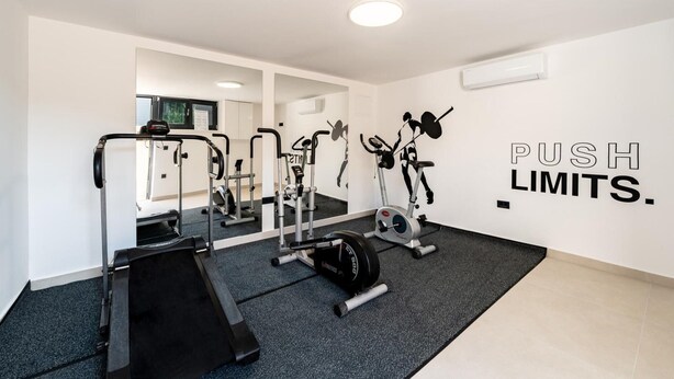 Un gimnasio con cinta de correr, banco de pesas y equipo de ejercicio.