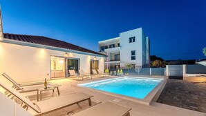 Un área de piscina moderna con sillones de descanso y una piscina.