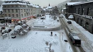 A snow-covered street with buildings, a church, and a sign for 'THERE' hotel. - Bright Apartment in Mont-dore (Mont-Dore)