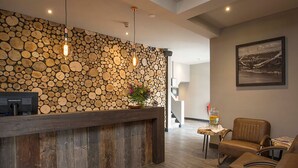 A reception area with a wooden log wall, a reception desk, leather chairs, and a framed picture on the wall. - Family Getaway w/Breakfast, Near Wassenaar Beach, Outdoors & Landmarks | 3 Units (Wassenaar)