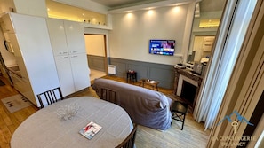 A modern living room with a dining table, sofa, and a TV mounted on the wall. - Summit hub by High Pass for 5 (Mont-Dore)