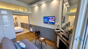 Ein modernes Hotelzimmer mit Bett, einer Couch, einem Fernseher, einem kleinen Tisch und einem Kamin.