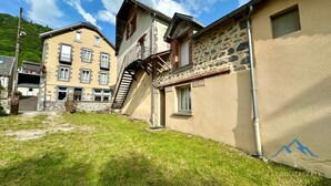 A building with a stone facade and a wooden staircase leading to a balcony. - Home for Groups and Families (Mont-Dore)