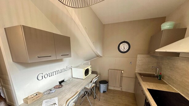 A compact kitchen with a microwave, a sink, and a clock on the wall. - Home for Groups and Families (Mont-Dore)