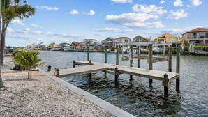 A waterfront property with a dock extending into calm water, surrounded by residential buildings and palm trees. - ENDLESS SUMMER. Beautiful waterfront vacation home (Apollo Beach)