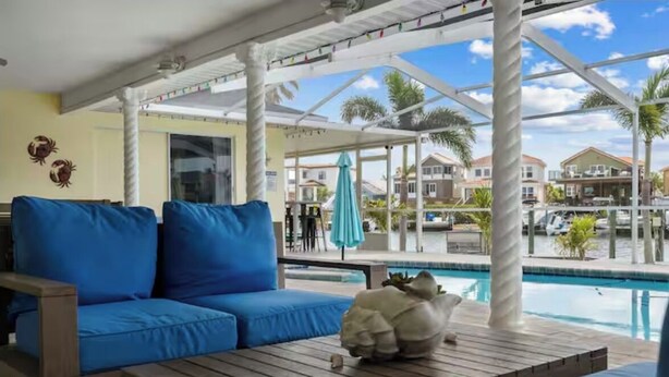 A poolside area with a blue sofa, a wooden table, and a decorative shell. - ENDLESS SUMMER. Beautiful waterfront vacation home (Apollo Beach)