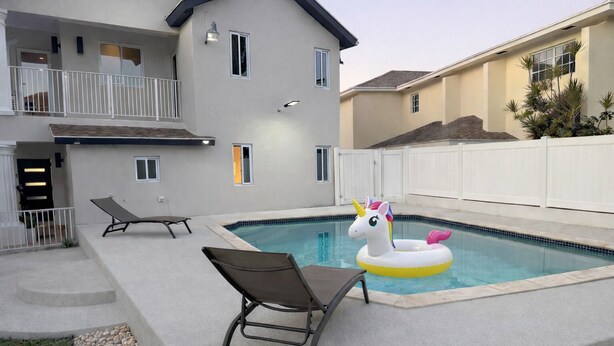Una piscina residenziale con poltrone sdraio e un gonfiabile a forma di unicorno.