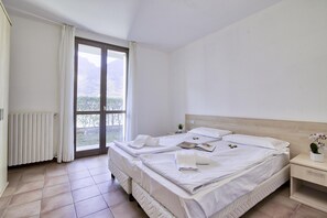 Une chambre d’hôtel propre et moderne, dotée d’un grand lit, d’une table de chevet et offrant une vue sur l’extérieur grâce à une porte-fenêtre coulissante.