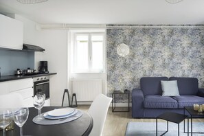 Eine moderne Küche mit weißen Schränken, einer schwarzen Arbeitsplatte und einem Essbereich mit Tisch für zwei Personen.