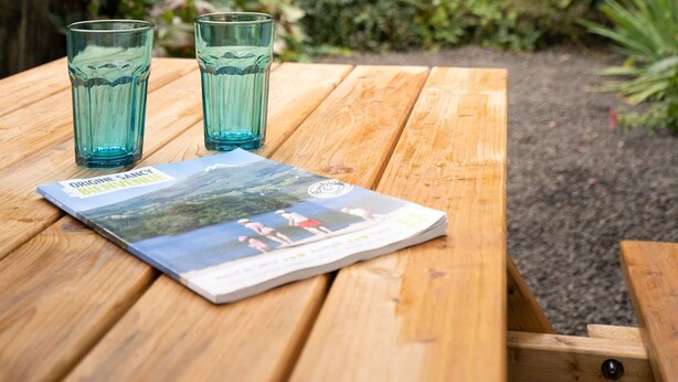 A wooden picnic table with two glasses and a magazine. - La Bourboule Quiet Villa or 5 (La Bourboule)