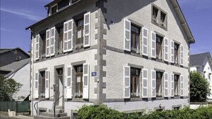 A two-story building with white exterior walls and multiple windows with shutters. - La Bourboule Quiet Villa or 5 (La Bourboule)