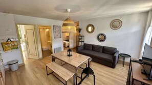 A modern living room with a wooden dining table, a grey sofa, and a hanging light fixture. - Modern 6-guest Flat in Mont-dore (Mont-Dore)