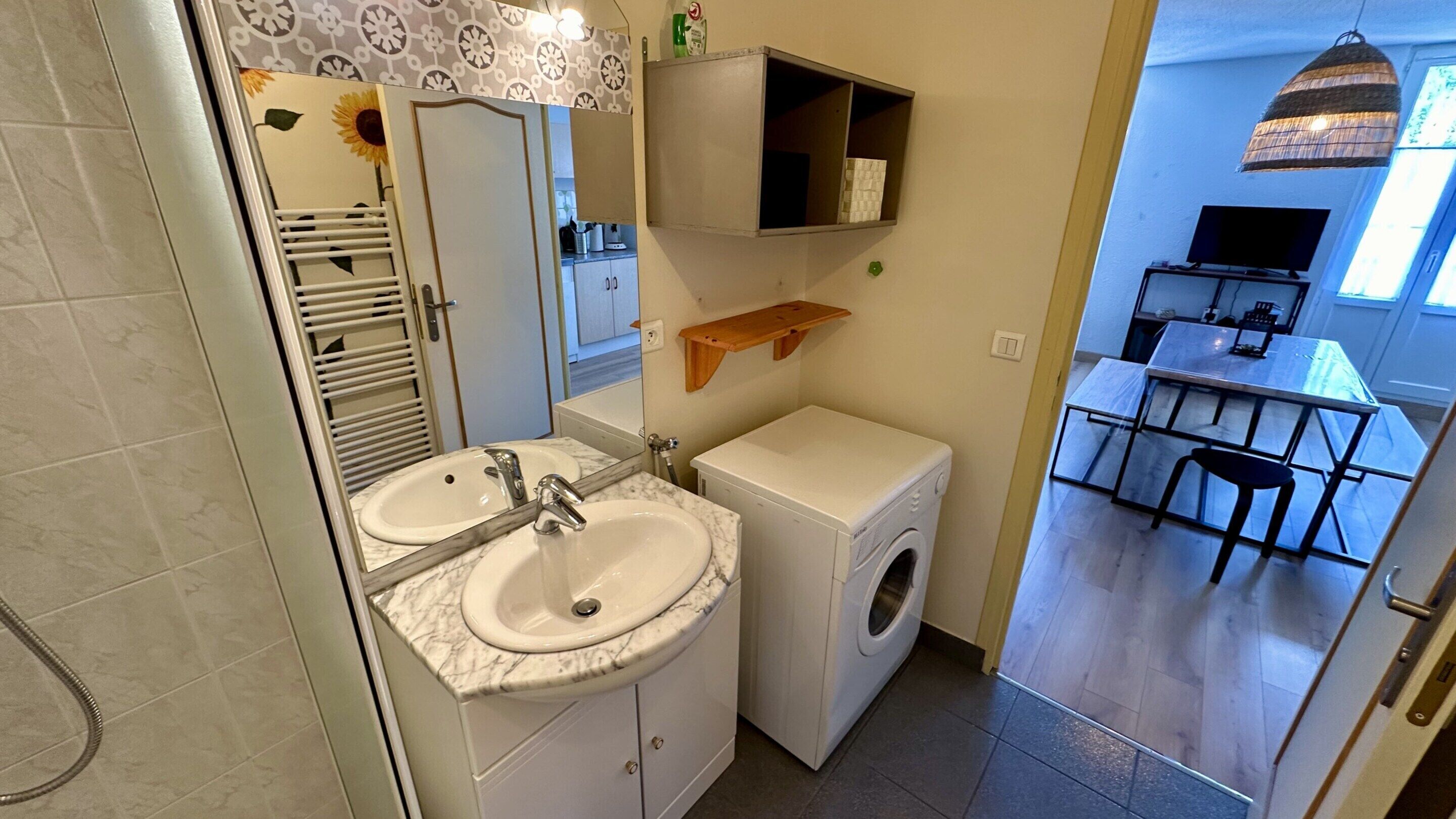 Un baño pequeño con lavamanos doble, lavadora y espejo.