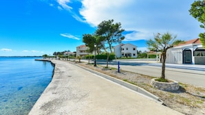 A coastal road with houses, a clear blue sky, and a calm sea. - Beachfront Apartment for 4 (Vir)
