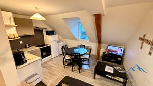 Una cocina compacta con electrodomésticos modernos, un comedor con una mesa redonda y un televisor en un rincón acogedor.