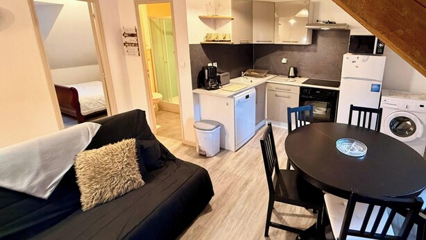 Un espacio habitable compacto con kitchenette, comedor y un dormitorio pequeño.