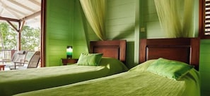 A room with two beds, green walls, and a wooden headboard.