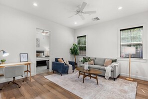 A modern living room with a ceiling fan, a sofa, a coffee table, a desk, and a chair.