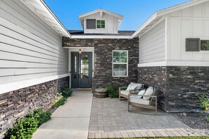 A residential building with a stone facade, a front door, and a small porch with a bench.