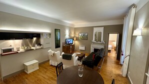 A compact living room with a flat-screen TV, a fireplace, a dining table, and a sofa. - Nature Refuge Near the Trail (Mont-Dore)