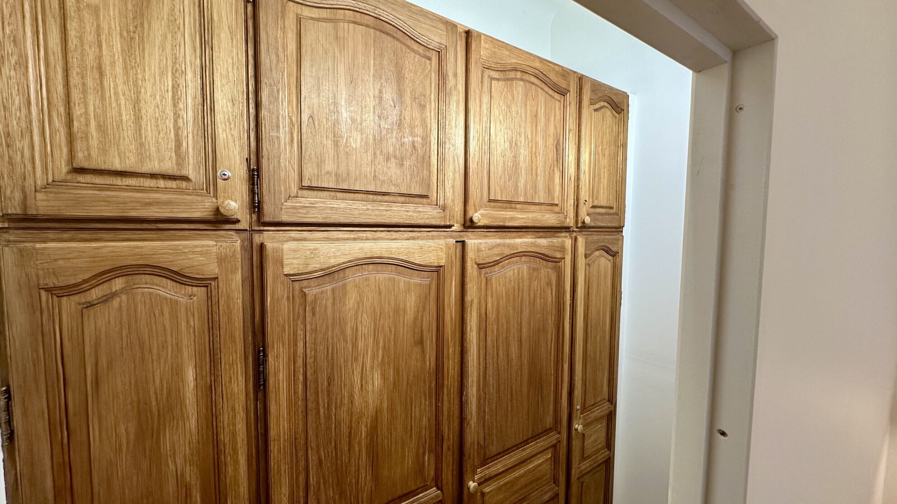 A wooden wardrobe with multiple doors and handles.