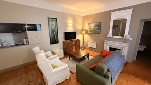 A living room with a fireplace, a television, and a sofa. - Nature Refuge Near the Trail (Mont-Dore)