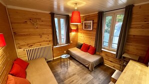 Una habitación acogedora de estilo cabaña con paredes de madera, una cama, un sofá y una mesa.