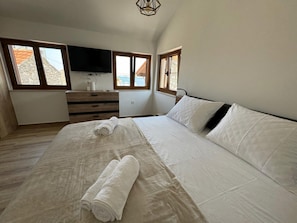 A bedroom with a large bed, two windows, a TV, and a wooden dresser. - Charming Seavie Retreat in Sukosan (Sukosan)