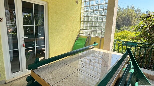 En balkong med ett biljardbord, en skjutdörr i glas och utsikt över grönområden.