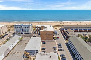 A building with a sign 'the SPINNAKER' and a parking lot with cars. - Atlantic Court 303 Steps to the beach (Ocean City)