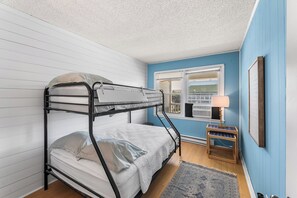 A bunk bed in a room with a window, a small table, and a lamp. - Atlantic Court 303 Steps to the beach (Ocean City)