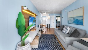 Ein modernes Wohnzimmer mit Sofa, Essbereich und einer Küche im Hintergrund.
