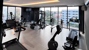 A modern gym with various exercise equipment, large windows, and a high ceiling. - Luxury Studio Apartments in Accra  (Accra)