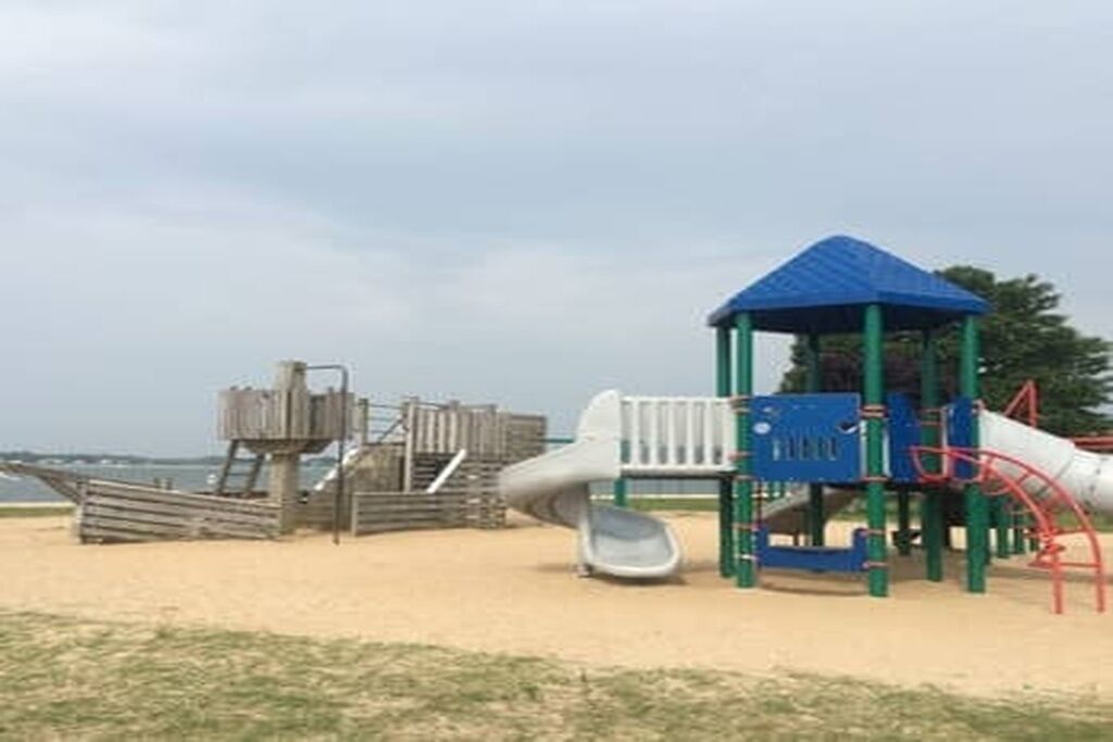 A playground with a blue-roofed playhouse, a slide, and a climbing structure.
