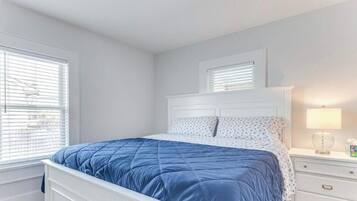 Une chambre à coucher avec un lit, une table de chevet, une lampe et une fenêtre avec des stores.