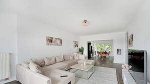 Una sala de estar moderna con un sofá seccional color beige, una mesa de centro y un televisor de pantalla plana sobre un mueble.