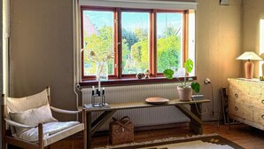 Una habitación con una silla de madera, un radiador, un escritorio con una planta y un aparador.